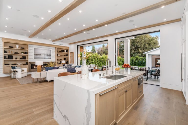 a large kitchen with a marble island and sink and living room